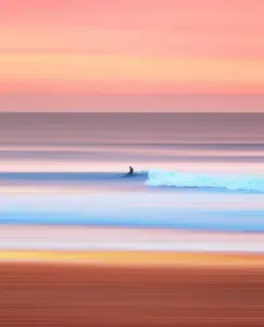 Man surfing at the beach. Sunset colors.