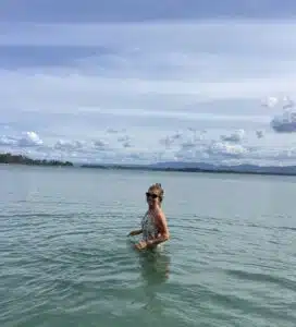 Cindy standing in the water at the beach. Blue sky and clouds behind her.